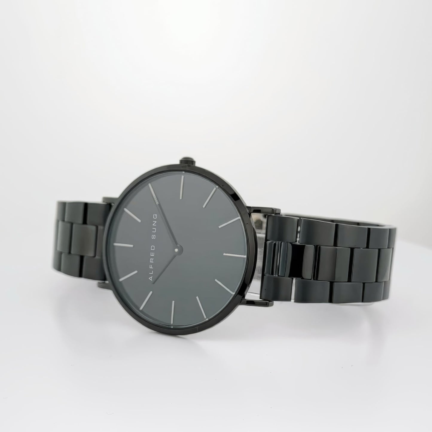 The Alfred Sung Metropolitan watch has a minimalist design with a black dial and bracelet against a white background.