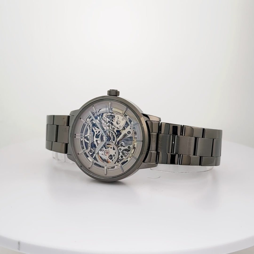 Alfred Sung Automatic III men's watch with grey skeleton dial and gunmetal bracelet, displayed on white stand.