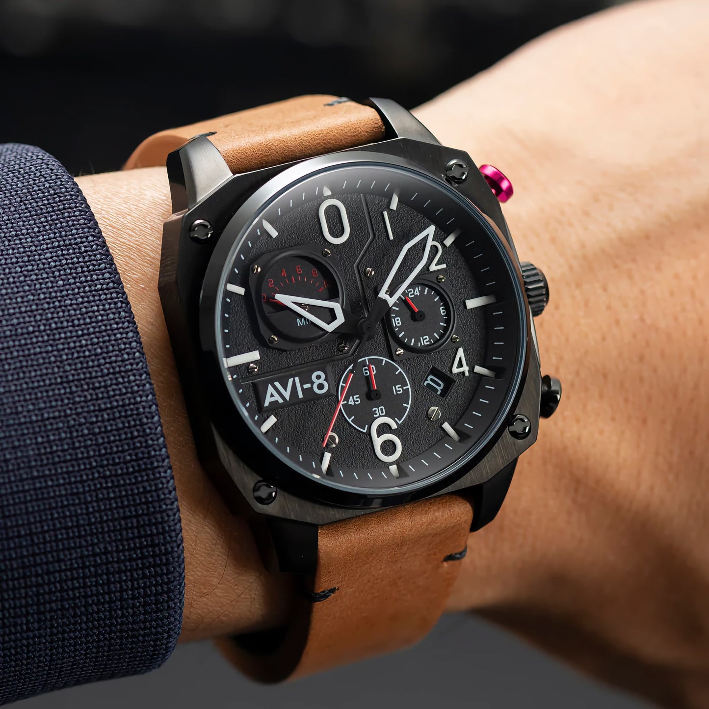 The AVI-8 Hawker Hunter Chronograph with a brown leather strap is worn in a dim setting, displaying the time.