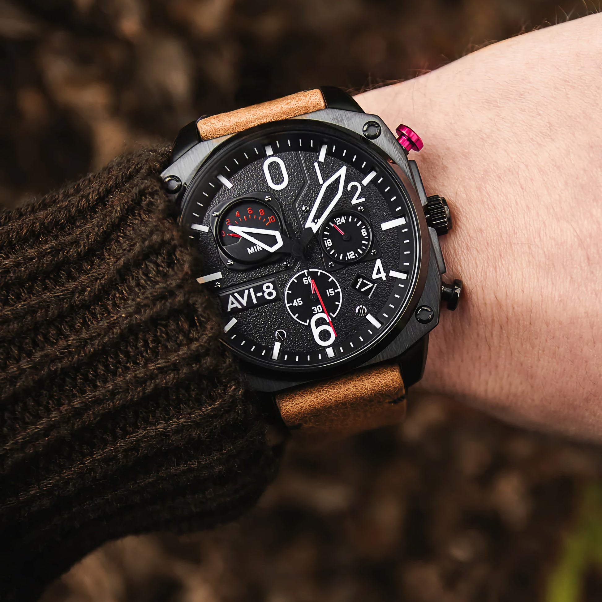 A wrist wearing an AVI-8 Hawker Hunter Retrograde watch with multiple dials and a dark sweater.