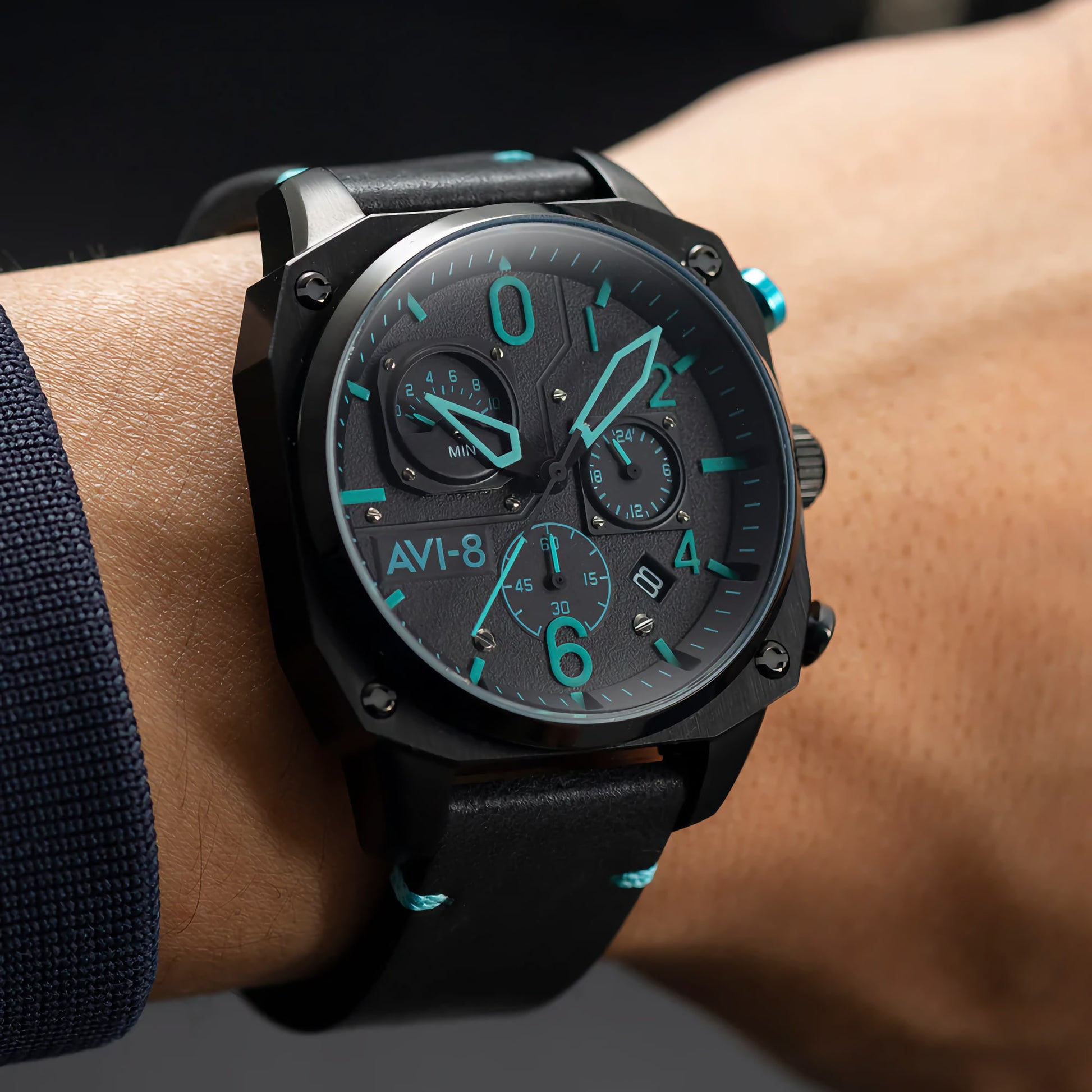 Close-up of a wrist wearing an AVI-8 Hawker Hunter Retrograde Chronograph with glowing blue accents and brown leather strap.