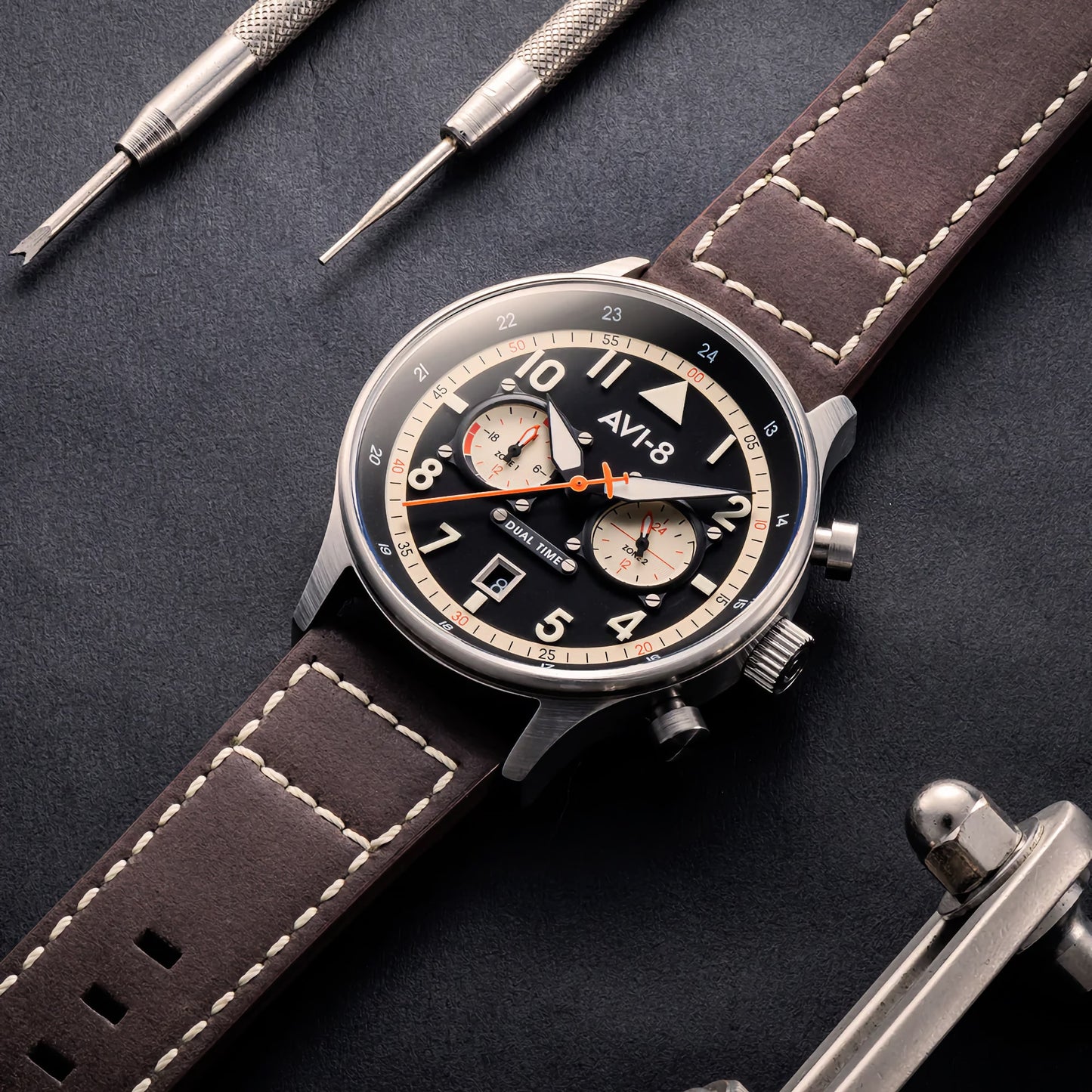 AVI-8 Hawker Hurricane Carey Dual Time Manston watch with a brown leather strap and black dial, amidst repair tools.