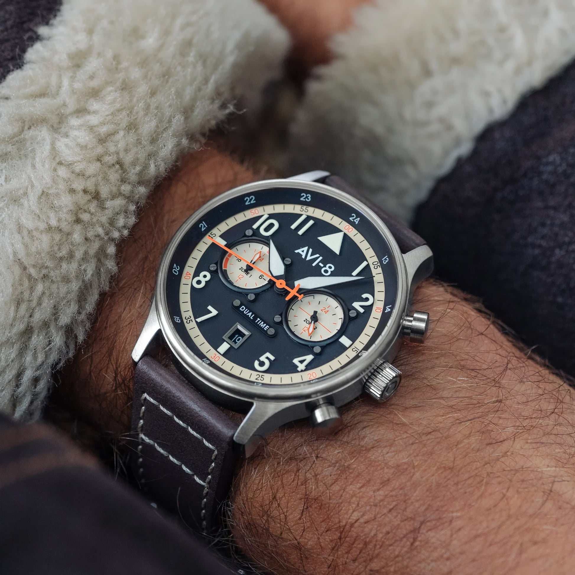 Close-up of AVI-8 Hawker Hurricane Carey Dual Time Manston with black dial, large numerals, and leather strap on a wrist.