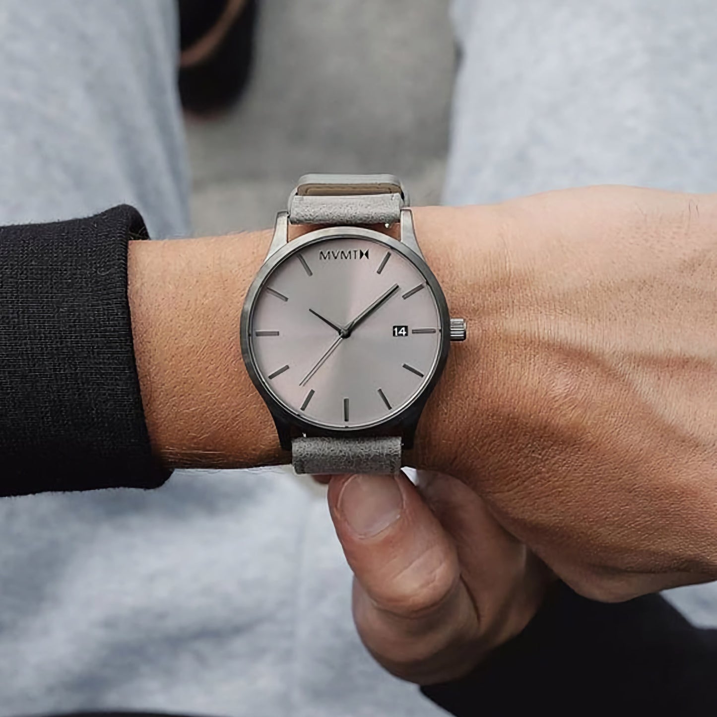 Close-up of MVMT Classic Monochrome Men's watch with a gray face and strap, date showing 14th.