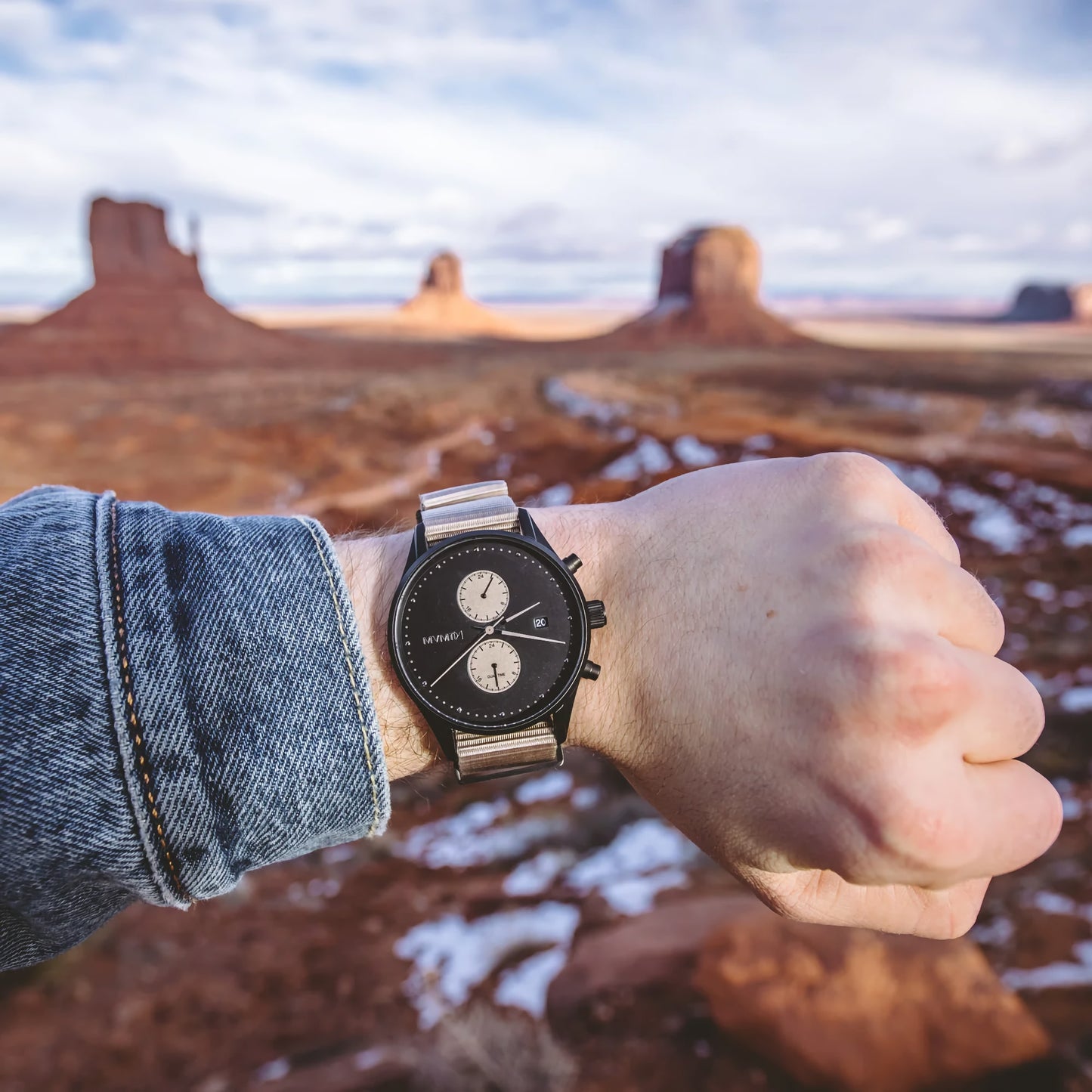 MVMT Voyager Desert Men's watch on wrist, dual time zones, set against striking rock formations.