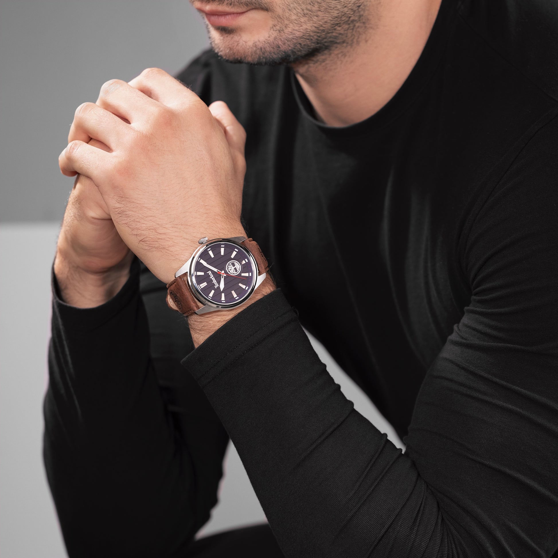 Man in a black sweater, hands clasped, wearing a Timberland Northbridge Watch with large face and leather strap.