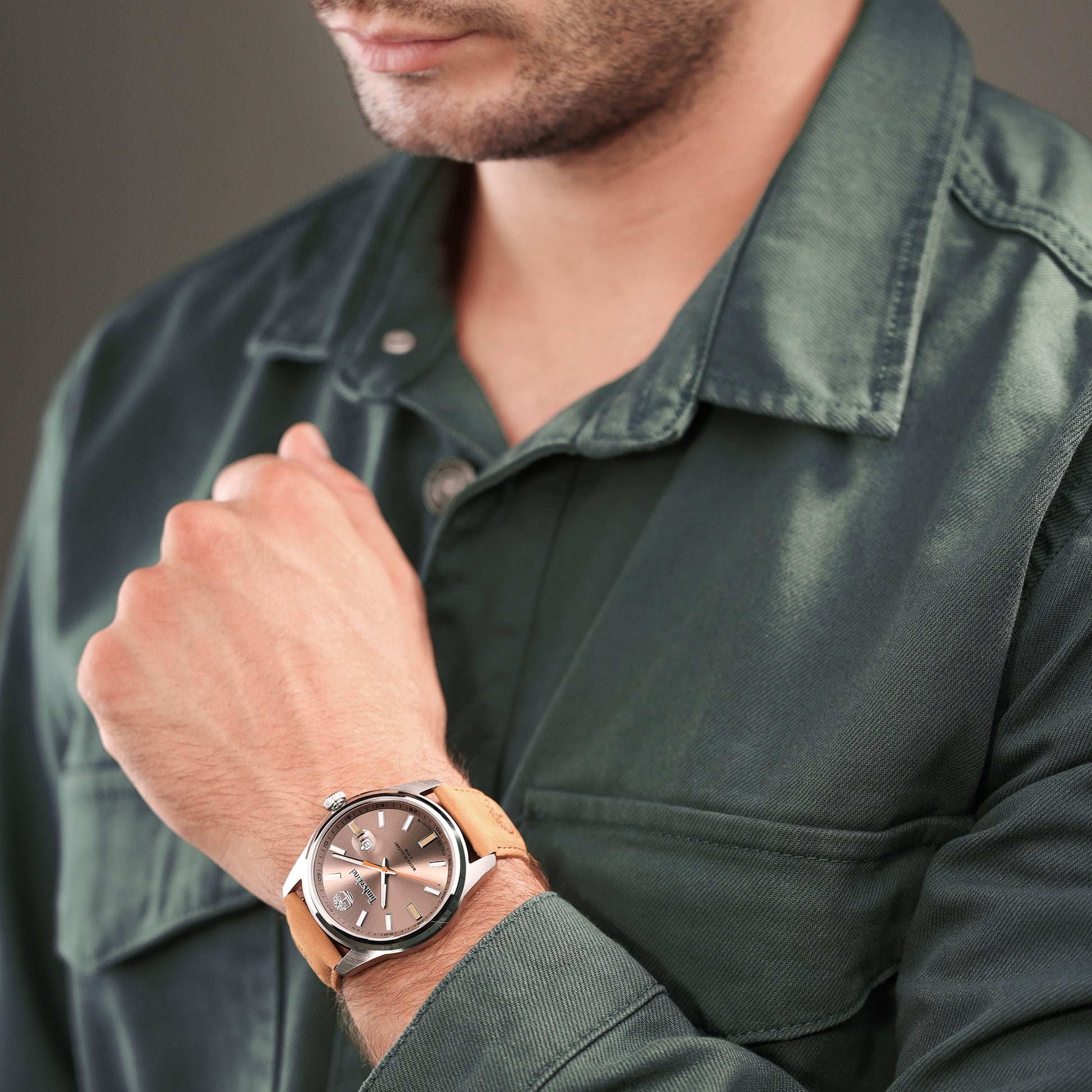 Person in a green shirt wearing a Timberland Orford watch with brown leather strap, touching their chin.
