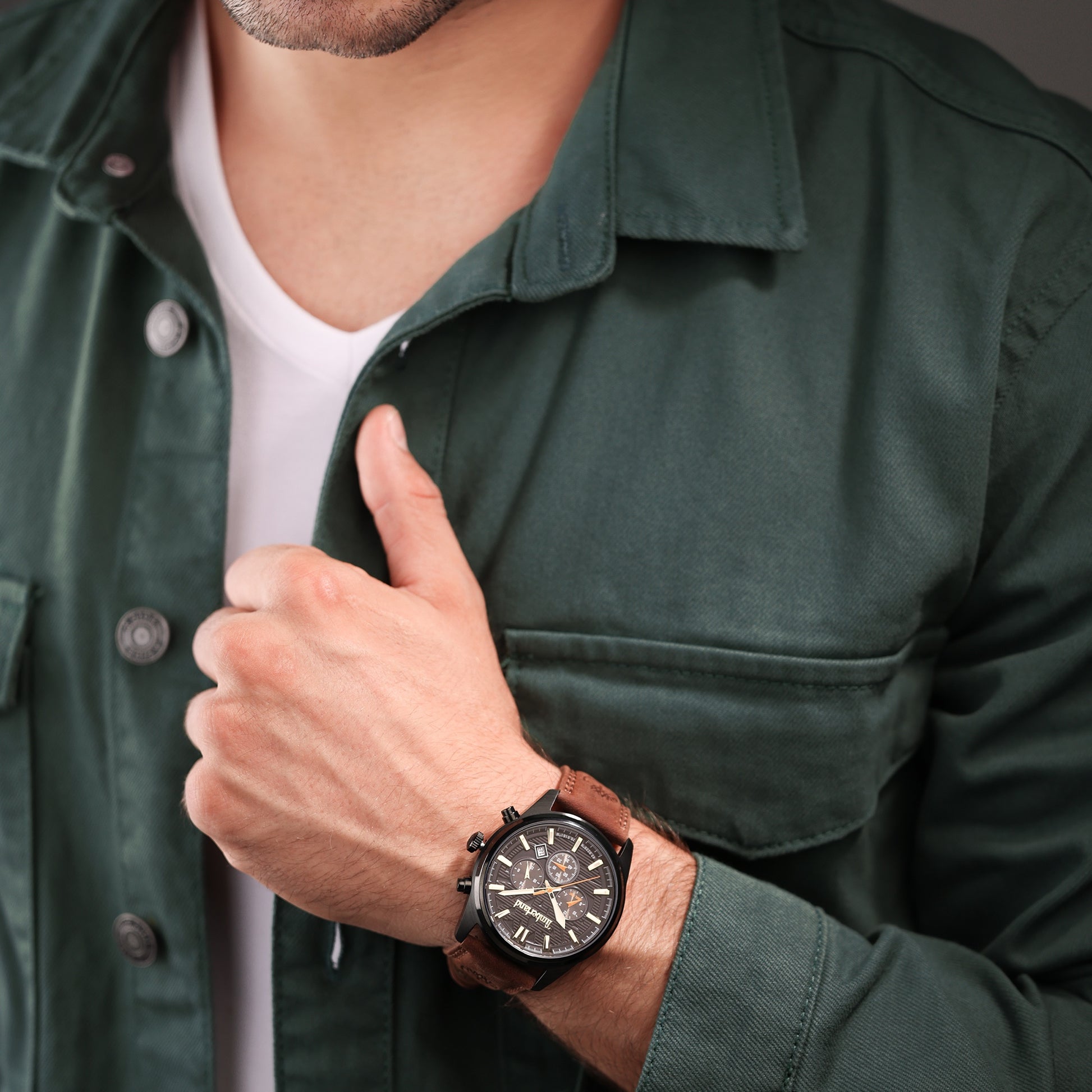 Man in green jacket giving a thumbs up, wearing a Timberland Northbridge watch with visible intricate dial design.
