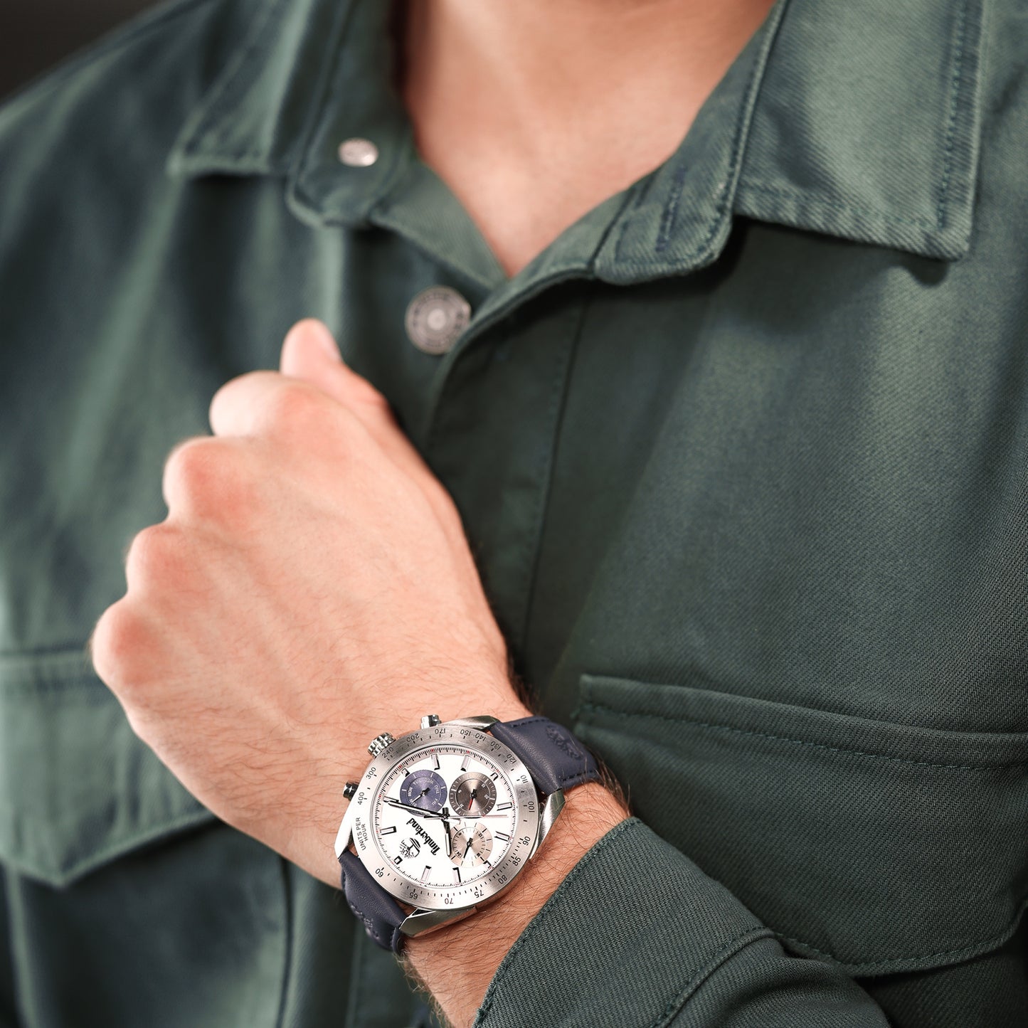 Person in a dark green jacket shows Timberland Carrigan watch with Japanese quartz movement and black leather strap.