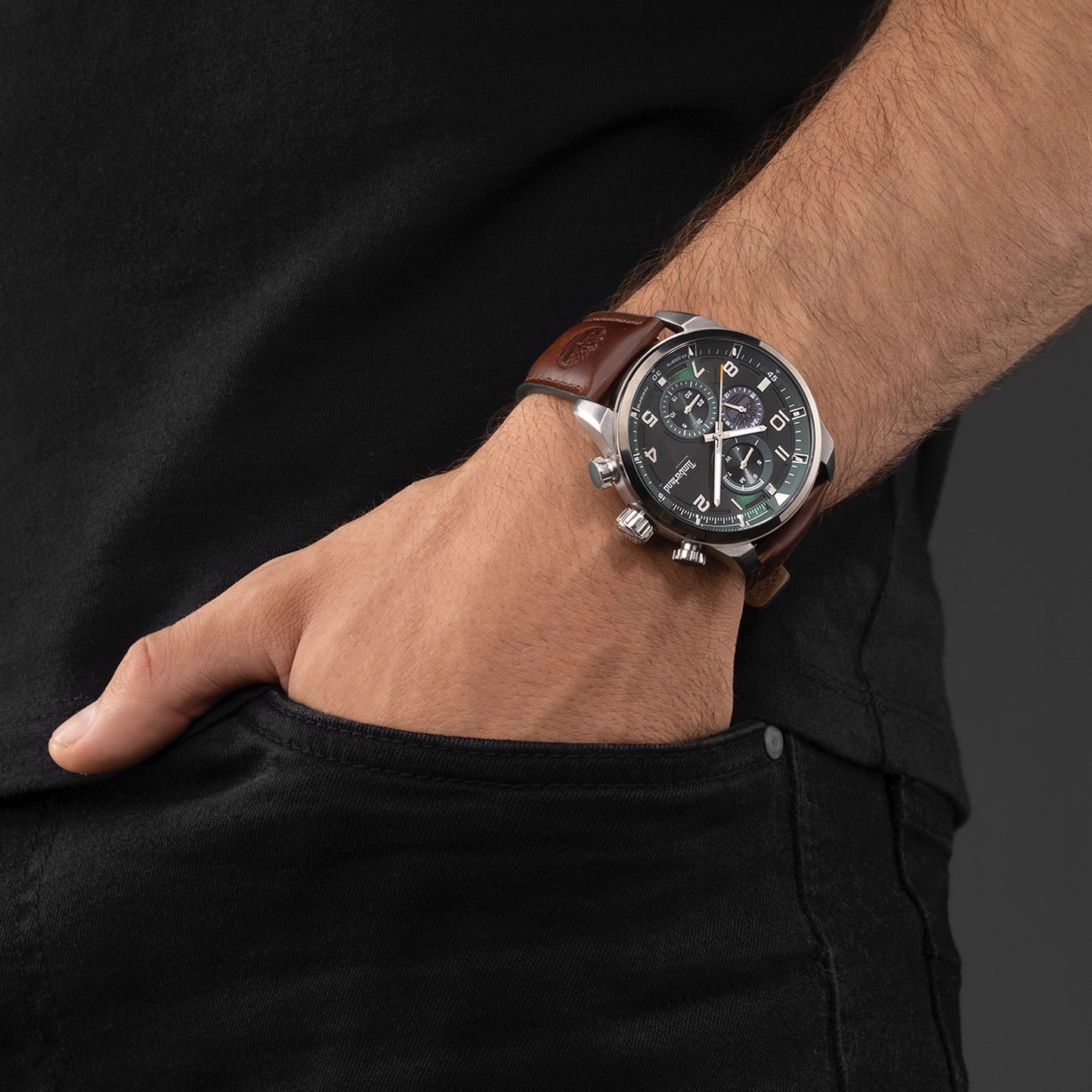 Man in black shirt, hand in pocket, models a Timberland Henniker II green dial multifunction men's watch.