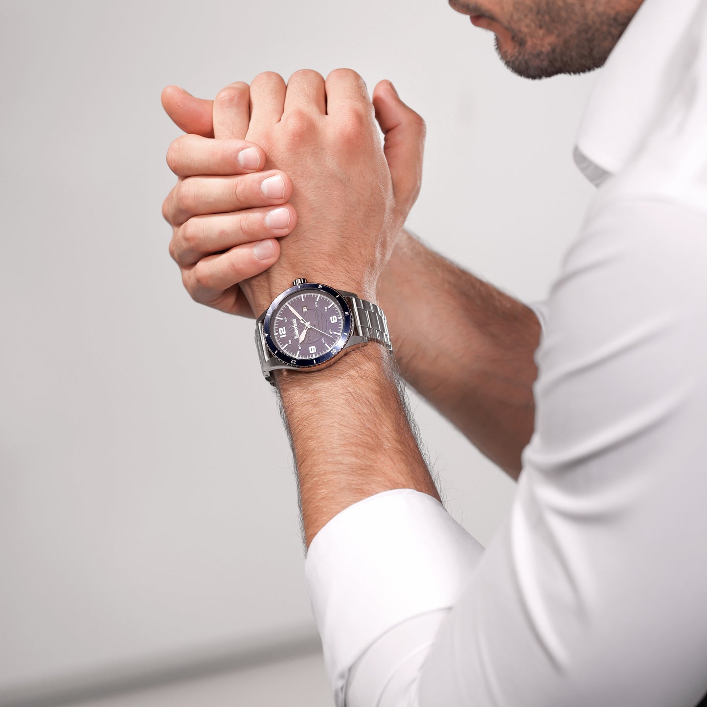 Person in white shirt clasping hands, featuring a silver Timberland Ashmont Stainless Steel & Link-Bracelet Watch.
