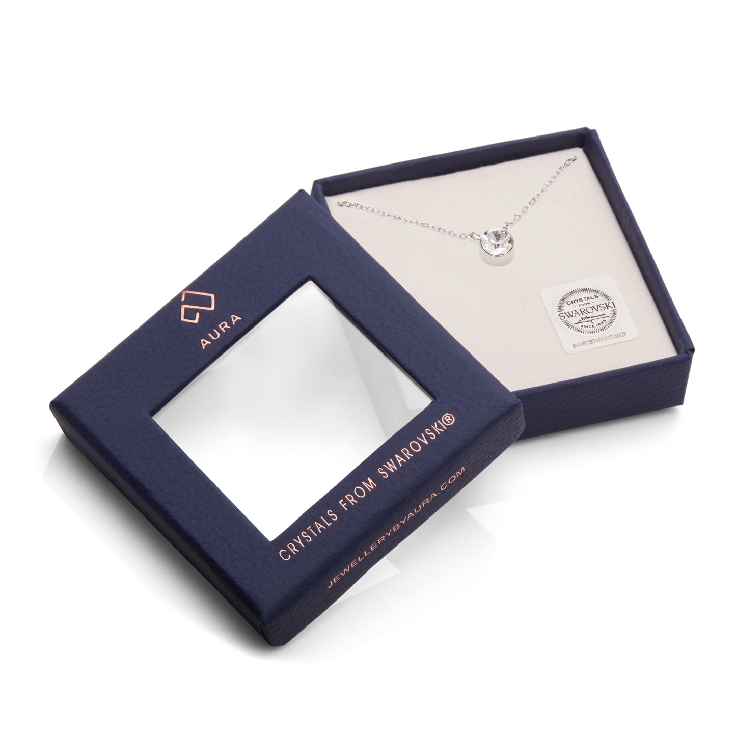 An elegant Pendant Necklace With Crystals featuring a crystal set in a shimmering silver design, beautifully presented in an open navy box with "Aura" highlighted on the lid.