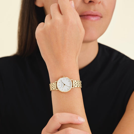 A person wears a Rosefield Small Edit White Gold Ladies Bracelet watch, touching their chin with one hand.